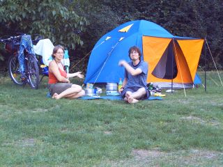 Christian und Jenny sitzen vor dem Zelt und kochen Essen