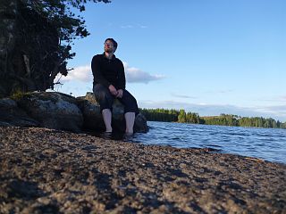 Ich sitze angestrahlt auf einem Fels und baumle mit den Fen im Wasser