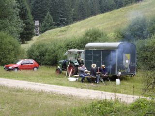 Panorama: Manes Auto, Traktor mit Bauwagen hinten dran, davor der Grill